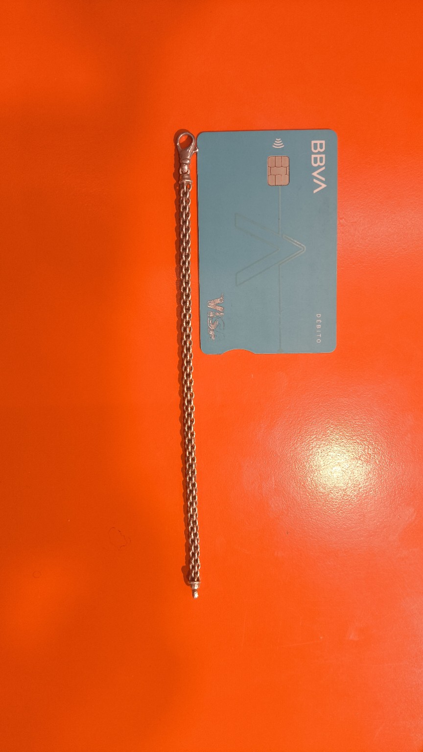 Brazalete junto a una tarjeta bancaria como referencia de escala